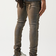 Person wearing brown distressed jeans and white sneakers on a white background