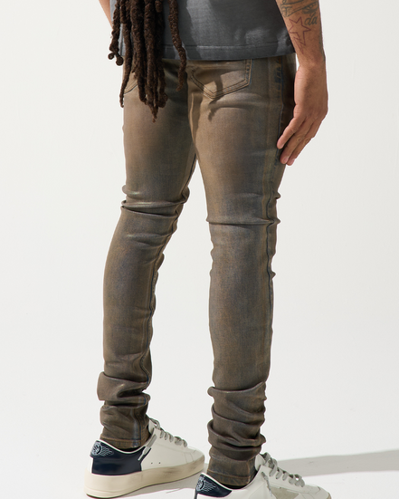 Person wearing brown distressed jeans and white sneakers on a white background