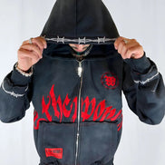 Person wearing a black hoodie with red text and designs on a white background