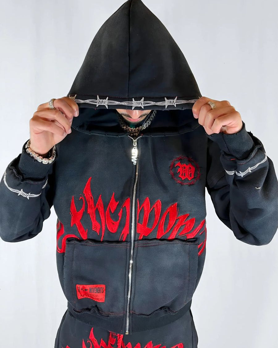 Person wearing a black hoodie with red text and designs on a white background
