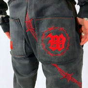 Black pants with red embroidered designs on a white background