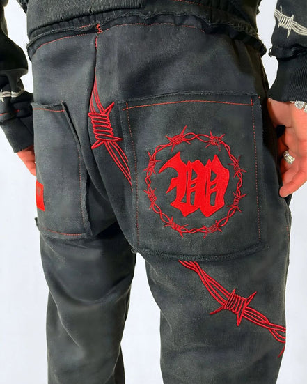 Black pants with red embroidered designs on a white background