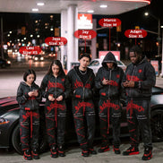 Five people wearing matching black outfits with red accents standing in front of a Petro Canada gas station at night.