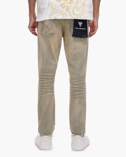 Person wearing beige pants and a white shirt with gold designs on a white background