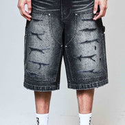 Person wearing black distressed denim shorts with a plain background