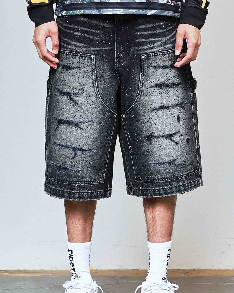 Person wearing black distressed denim shorts with a plain background