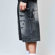 Person wearing a black and white outfit with a denim skirt and sneakers.