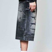 Person wearing a black denim skirt with a plain background