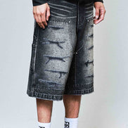 Person wearing black acid-wash jeans, white sneakers, and socks with text on a plain background