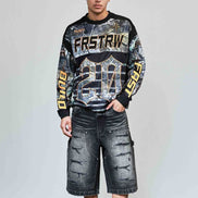 Person wearing a patterned sweatshirt and denim shorts against a plain background