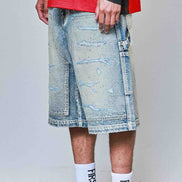 Person wearing distressed denim shorts, white sneakers with black Nike logo, and red shirt.