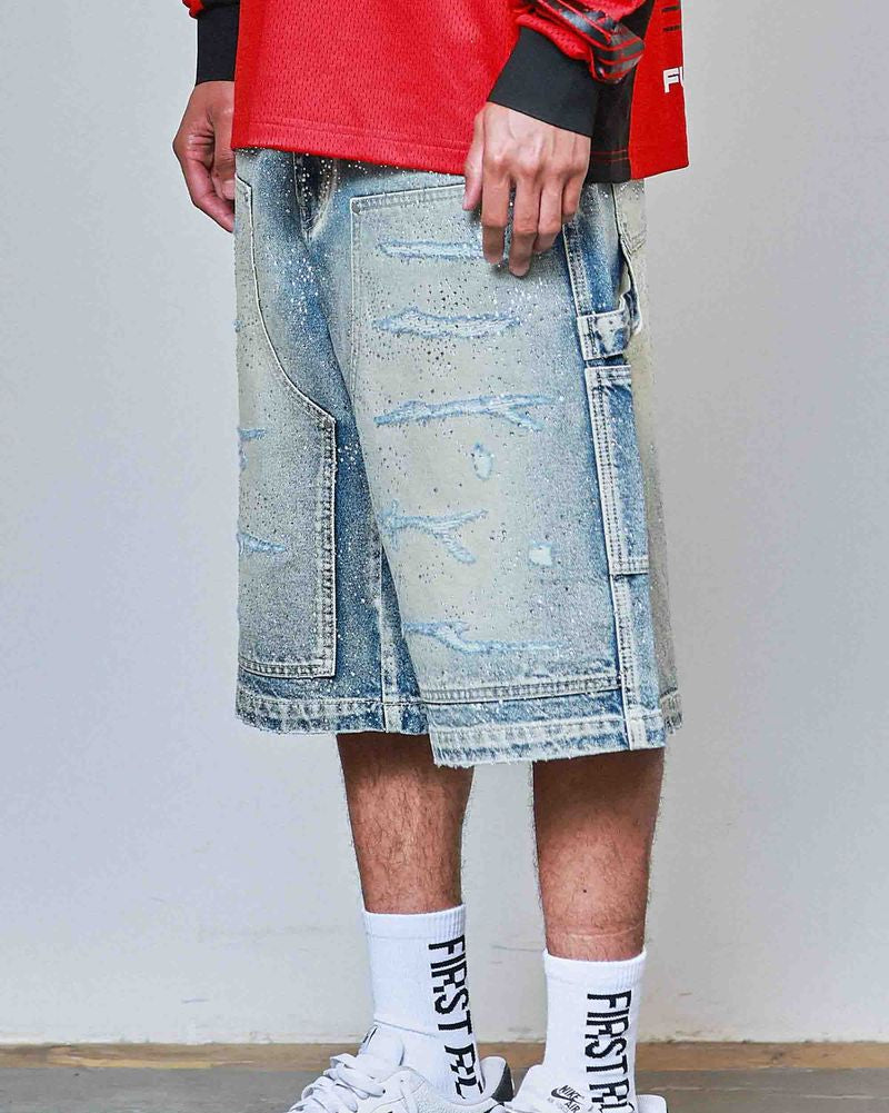 Person wearing distressed denim shorts, white sneakers with black Nike logo, and red shirt.