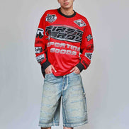 Person wearing a red sweatshirt with branding and denim shorts on a plain background