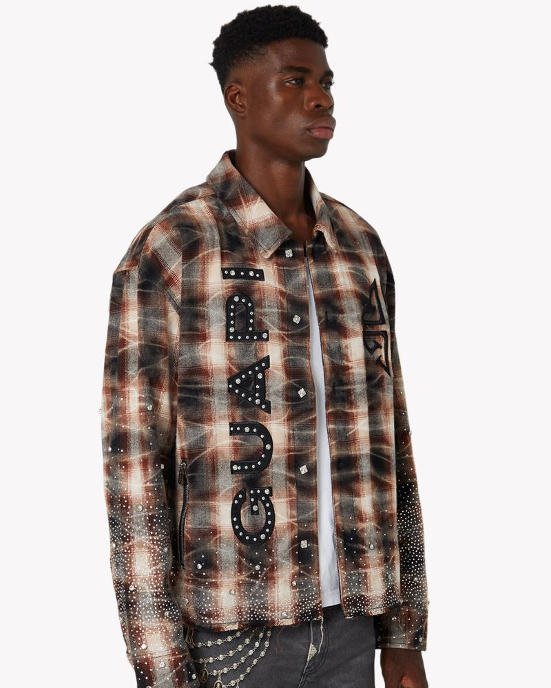 Man wearing a plaid shirt with studded details and 'GUAPI' branding.