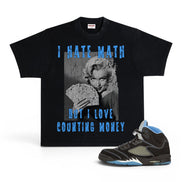 A black graphic t-shirt featuring a Marilyn Monroe print with the text 'I HATE MATH BUT I LOVE COUNTING MONEY' in distressed blue lettering, shown alongside a black and light blue sneaker on a white background.