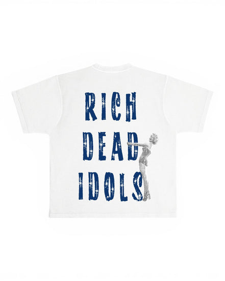 A white short-sleeve t-shirt with a graphic print on the front. The design features the text 'RICH DEAD IDOLS' in a distressed blue font, with a gray silhouette of Marilyn Monroe holding a microphone integrated into the lettering.