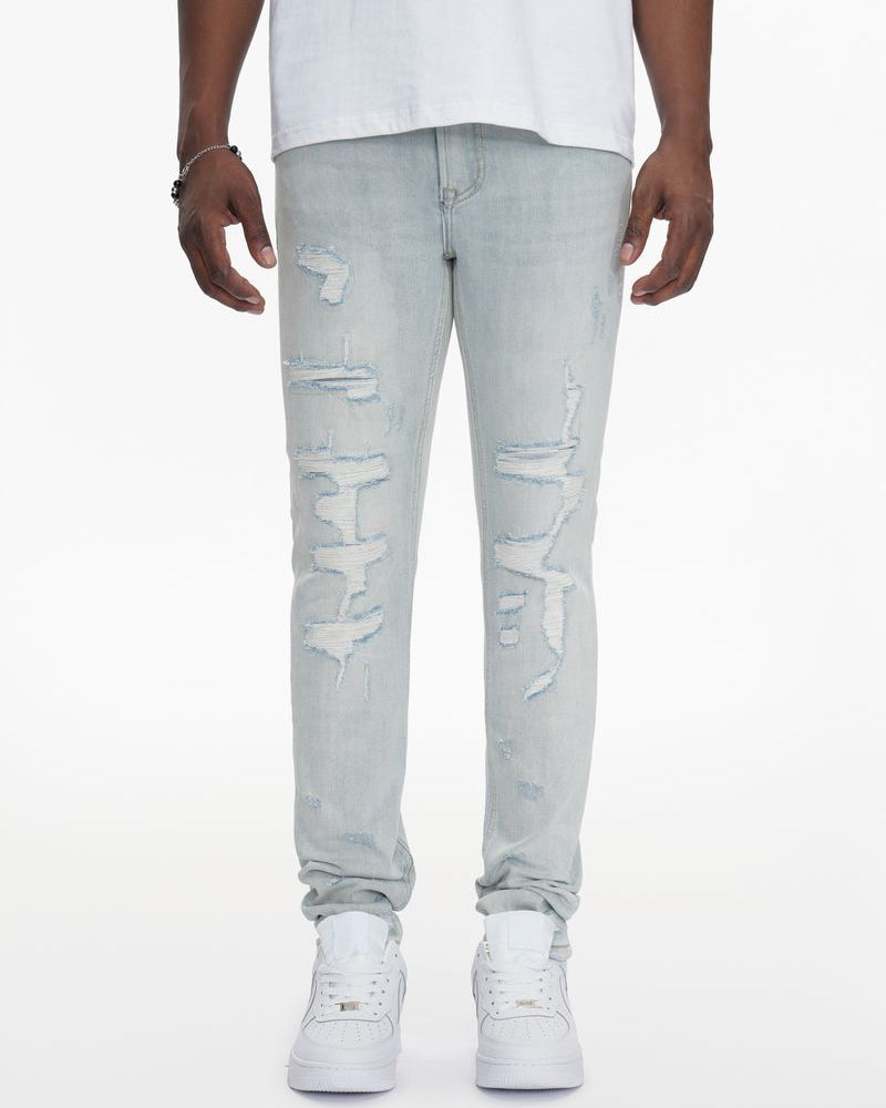 Person wearing light gray distressed jeans and white sneakers on a white background