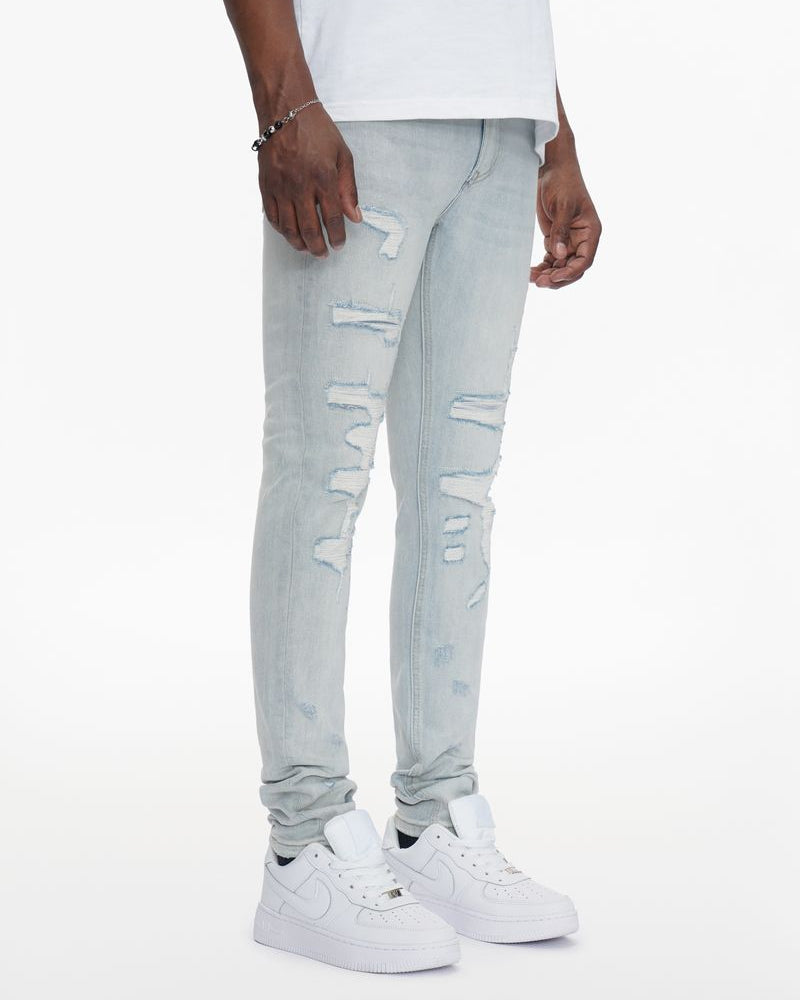 Person wearing light blue ripped jeans and white sneakers on a white background