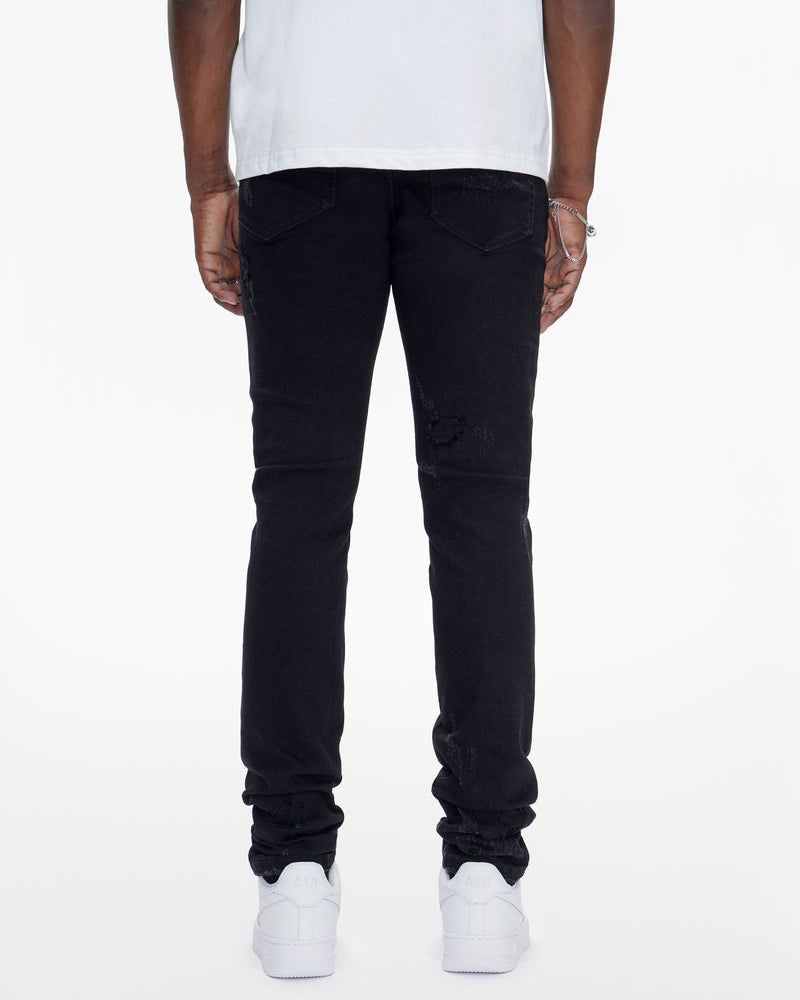 Person wearing black jeans and white sneakers on a white background