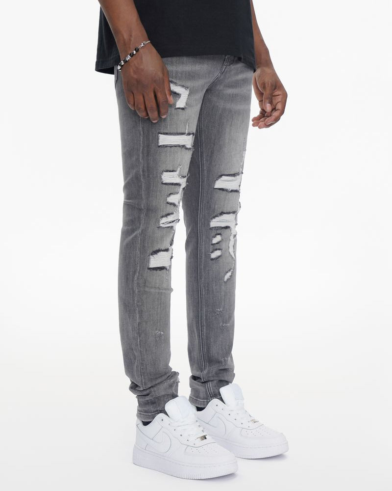 Person wearing gray distressed jeans and white sneakers on a white background