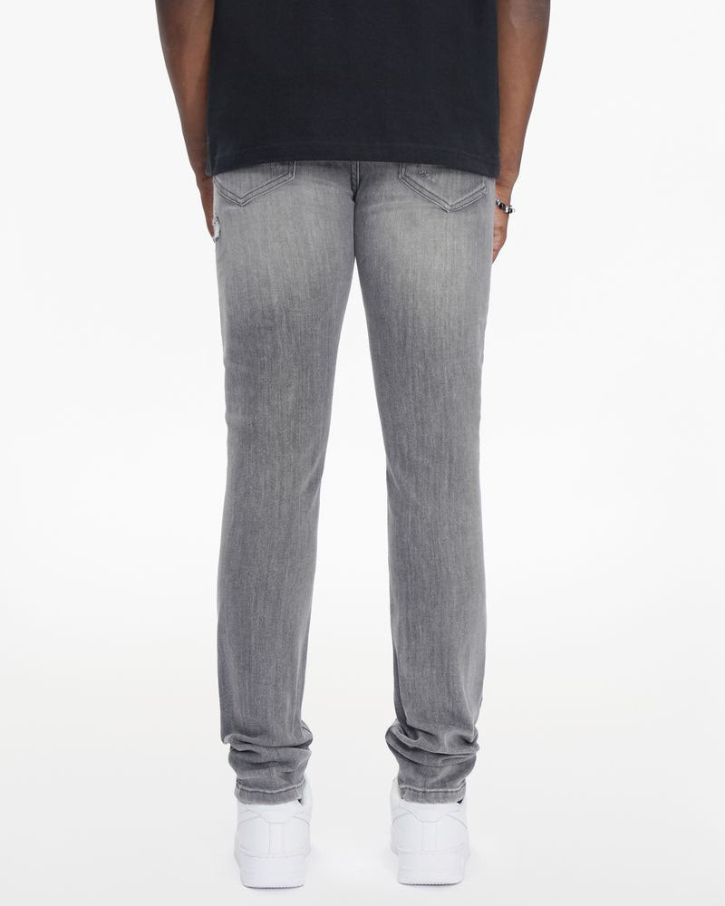 Person wearing gray jeans and white sneakers on a white background