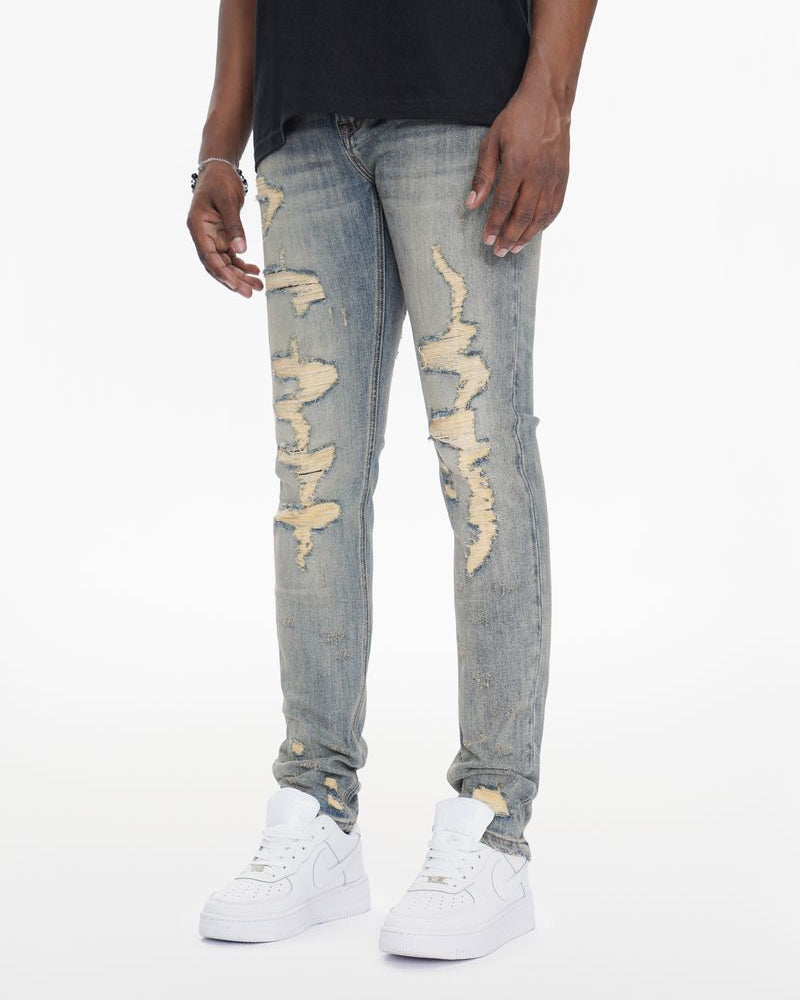 Person wearing distressed light blue jeans and white sneakers on a white background