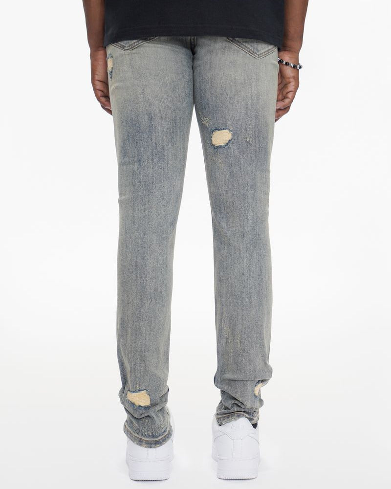 Person wearing light gray distressed jeans on a white background