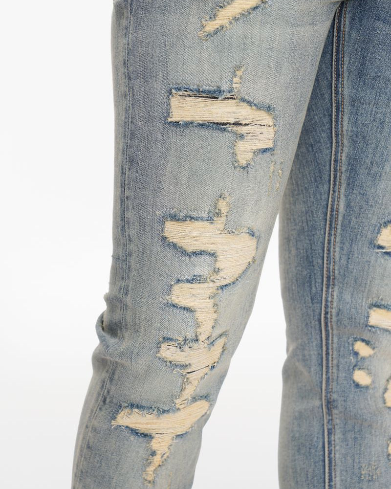 Close-up of distressed blue jeans on a white background