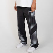Person wearing black and white striped pants with a brand logo on a white background