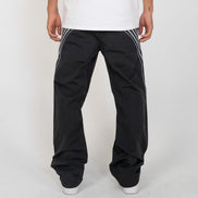 Person wearing black pants with white stripes on a white background