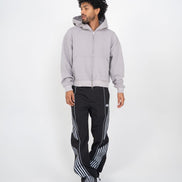 Man wearing a gray hoodie and black pants with white stripes on a white background