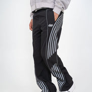 Person wearing black track pants with white stripes and a gray hoodie on a white background