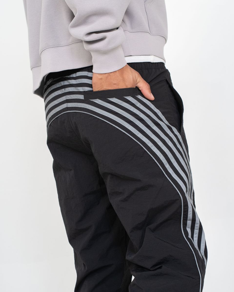 Black pants with gray stripes worn by a person on a white background