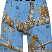 Blue camouflage boxer briefs featuring a Realtree Edge woodland camo pattern with branches, leaves, and bark, and a black 'PSD' logo printed on the front waistband.