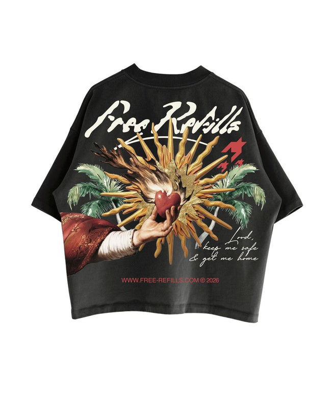 A black short-sleeve graphic t-shirt featuring a large vintage-style print on the back. The graphic depicts a hand holding a red heart amidst golden rays, flanked by green palm trees, with the text 'Free Refills' in white script at the top and 'www.free-refills.com'