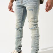 Person wearing light blue distressed jeans and white sneakers with black stripes on a white background
