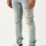 Person wearing light blue ripped jeans and white sneakers with black stripes on a white background