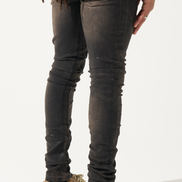 Person wearing dark distressed jeans and brown shoes on a white background