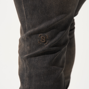 Close-up of dark brown pants with a brand logo on a white background