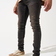 Person wearing dark distressed jeans and beige sneakers on a white background