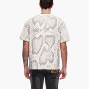 Person wearing a white t-shirt with snake print pattern on the back, standing against a white background.