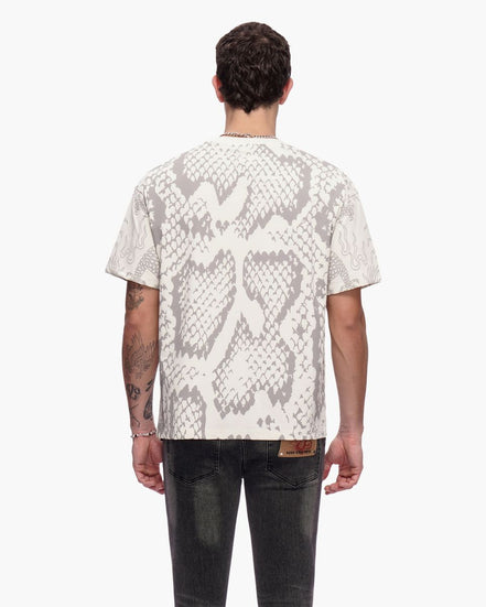 Person wearing a white t-shirt with snake print pattern on the back, standing against a white background.