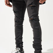 Person wearing black ripped jeans and black and white sneakers on a white background