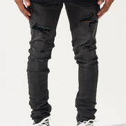 Person wearing black distressed jeans and black and white sneakers on a white background