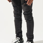Person wearing black ripped jeans and black and white sneakers on a white background
