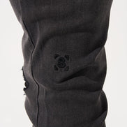 Close-up of black pants with a brand logo on a white background