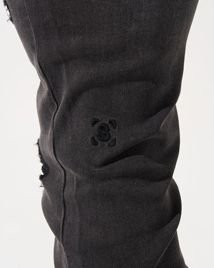 Close-up of black pants with a brand logo on a white background
