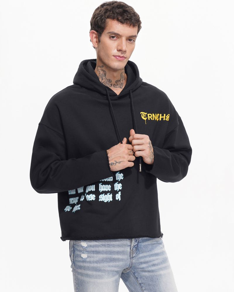 Person wearing a black hoodie with text, standing against a white background