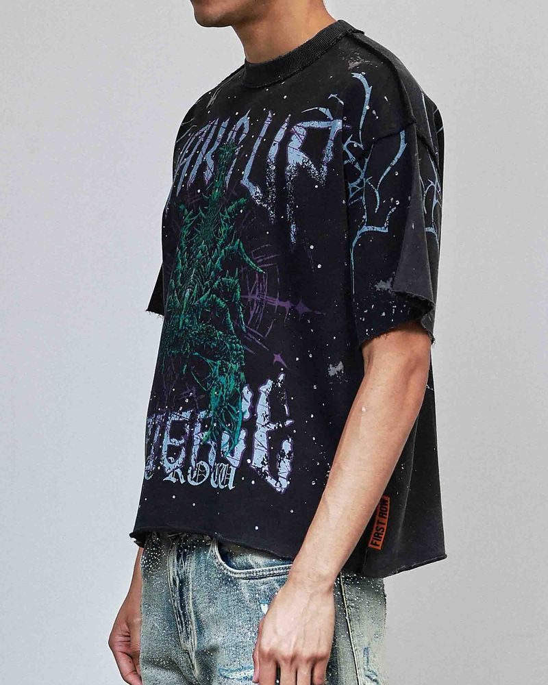 Person wearing a black graphic t-shirt with colorful designs on a plain background