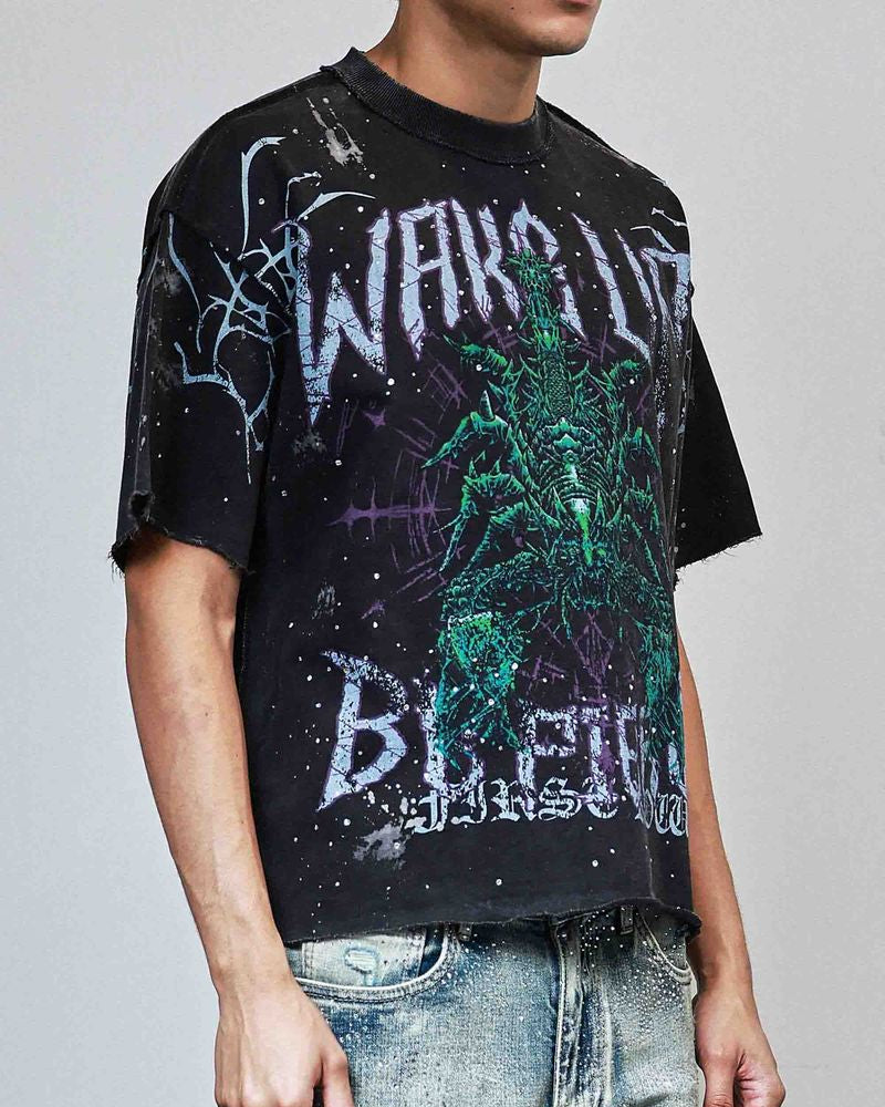 Person wearing a black t-shirt with graphic design and text, standing against a plain background